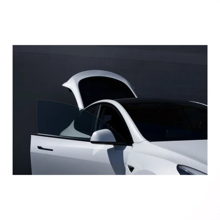 White Tesla Model Y with open rear door and rear hatch, showcased against a dark gray background in a modern automotive setting.