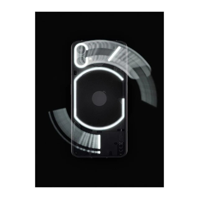 The back of a black smartphone is shown with illuminated glyphs. The phone is centered against a black background with motion blur effects.