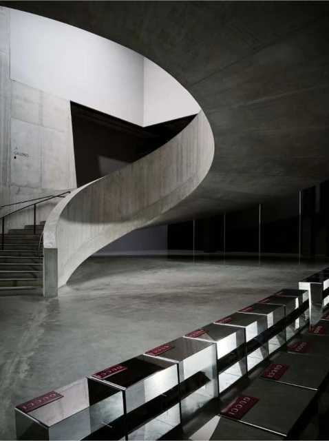 Interior view of a modern building with a spiral staircase and rows of metallic displays, showcasing contemporary architectural design.