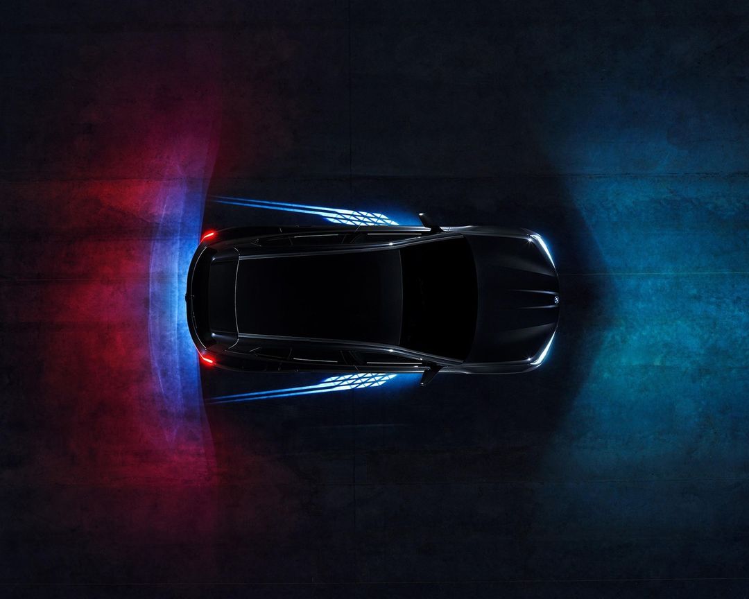 Aerial view of a black sports car on dark asphalt with dynamic lighting, showcasing sleek automotive design and modern technology.