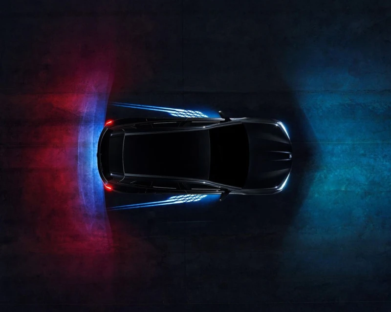 Aerial view of a black sports car on dark asphalt with dynamic lighting, showcasing sleek automotive design and modern technology.