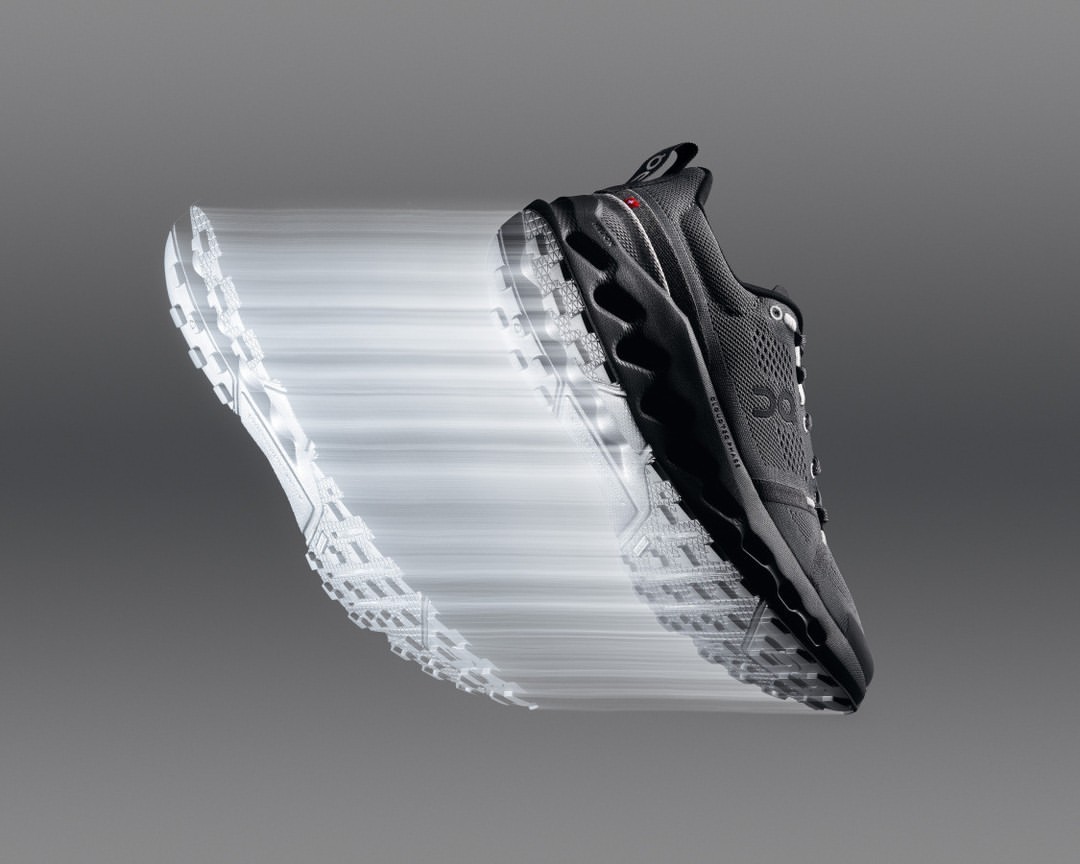 Motion blur photo of a single On trail running shoe, floating against a gray background, showcasing athletic design and technology.