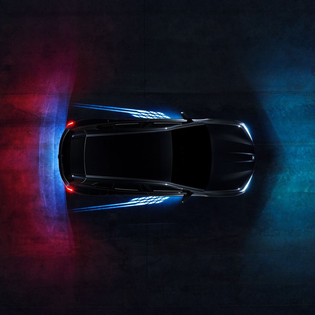 Aerial view of a sleek black car with illuminated accents, showcasing modern automotive design against a dark concrete backdrop.