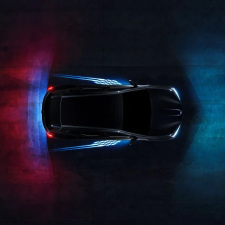 Aerial view of a sleek black car with illuminated accents, showcasing modern automotive design against a dark concrete backdrop.