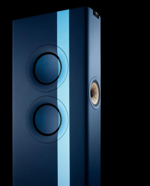 Close-up of a modern floor-standing loudspeaker in matte blue, featuring circular sound-generating units and a vertical light stripe.