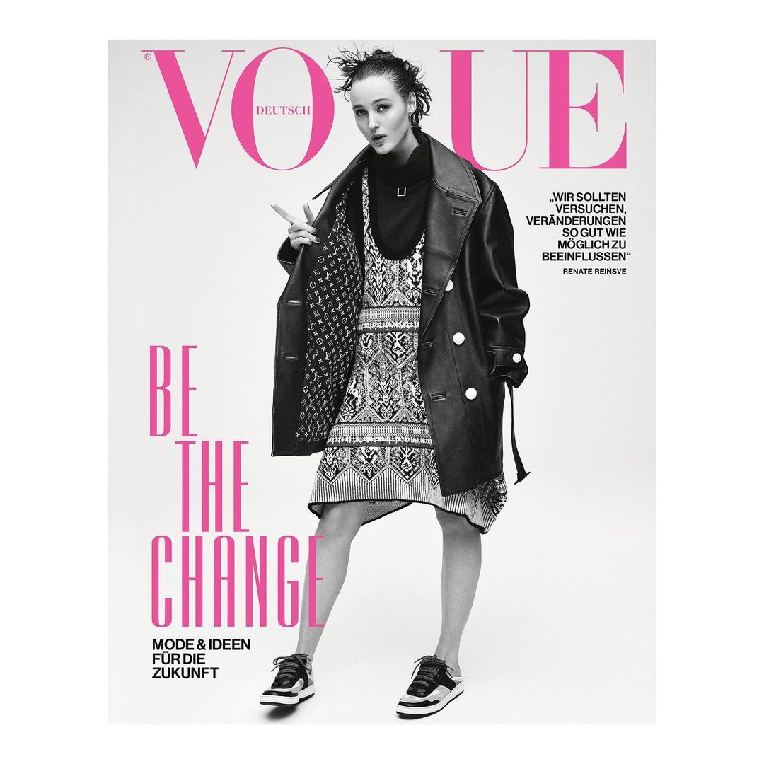 Vogue Deutsch cover featuring a young woman in a black coat and patterned dress, posing confidently against a clean, white backdrop.