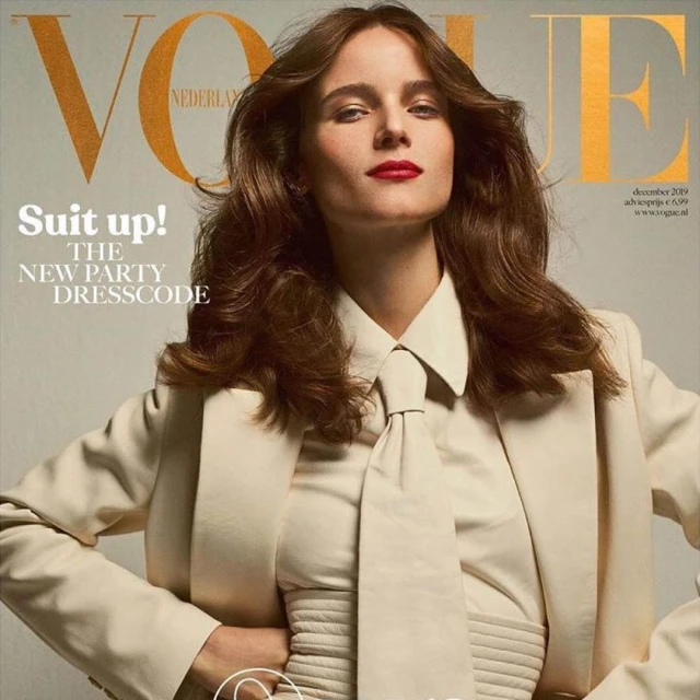 Vogue magazine cover featuring a woman with brown hair wearing a beige suit and tie looking directly at the viewer.