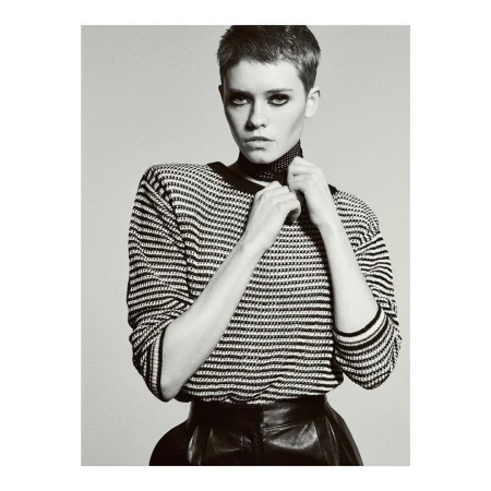 Monochrome portrait of a woman with short hair wearing a striped sweater and leather skirt against a plain background.