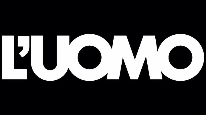 Bold typographic logo of L'UOMO magazine against a solid black background, featuring high contrast and modern sans-serif font.