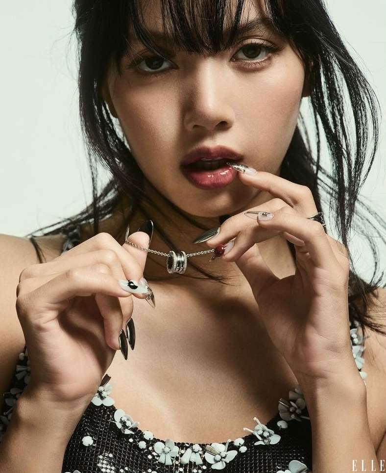 Close-up studio portrait of a South-East Asian adult female model with dark hair and long black nails, holding a silver Bulgari necklace.