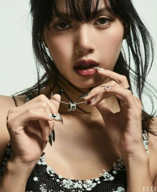 Close-up studio portrait of a South-East Asian adult female model with dark hair and long black nails, holding a silver Bulgari necklace.