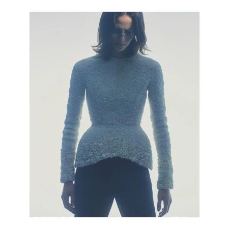 Model in textured light blue long-sleeve top and dark trousers against white background by Gregory Harris