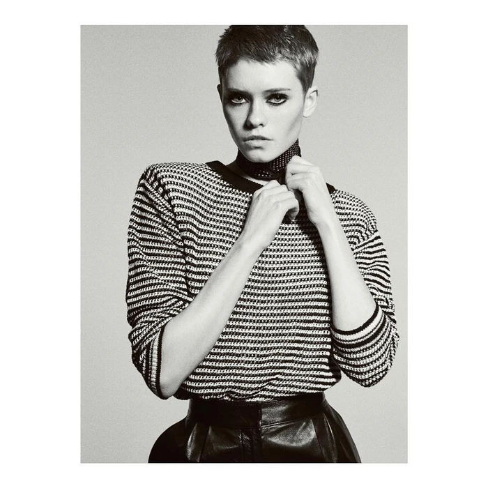 Monochrome portrait of a woman with short hair wearing a striped sweater and leather skirt against a plain background.