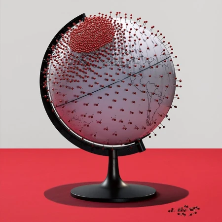 A world globe densely stuck with numerous red pins on a stand against a red and white background
