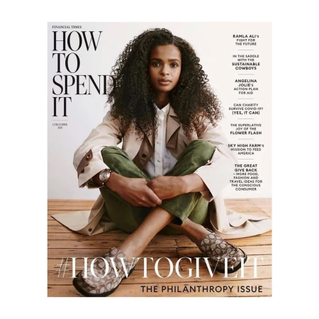 Magazine cover featuring a woman with curly hair, wearing a trench coat and green pants, seated on a wood floor.