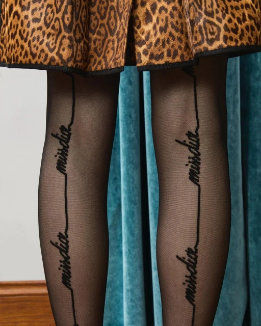 Close-up studio shot of a skirt with a leopard print and black tights with the words 'miss dior' printed vertically on the legs.