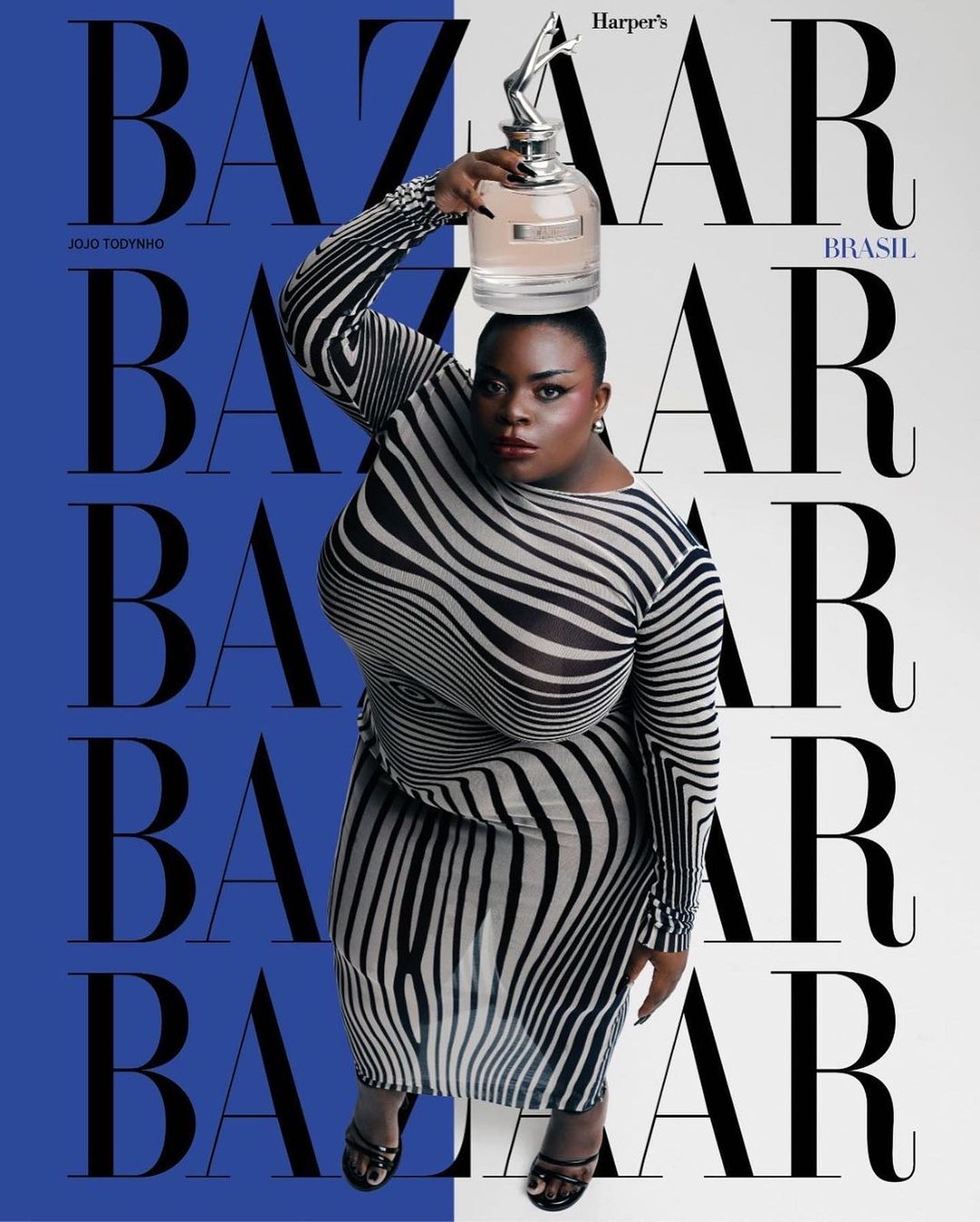 Magazine cover featuring plus-size woman in zebra-striped dress balancing perfume bottle on her head against blue and white background.