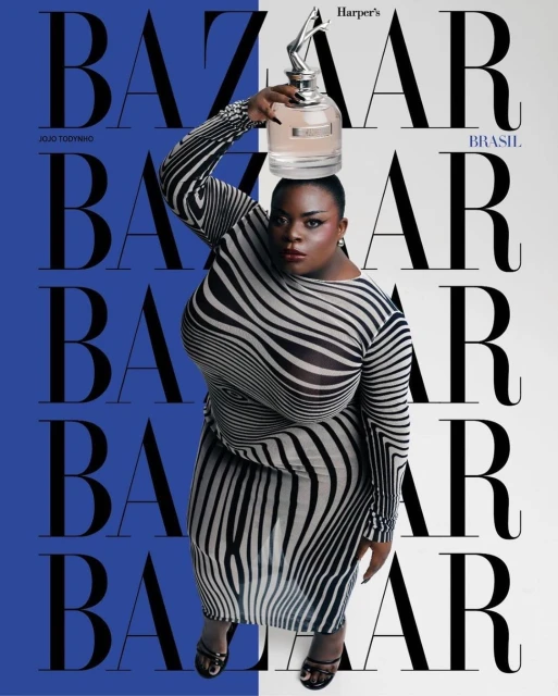 Magazine cover featuring plus-size woman in zebra-striped dress balancing perfume bottle on her head against blue and white background.