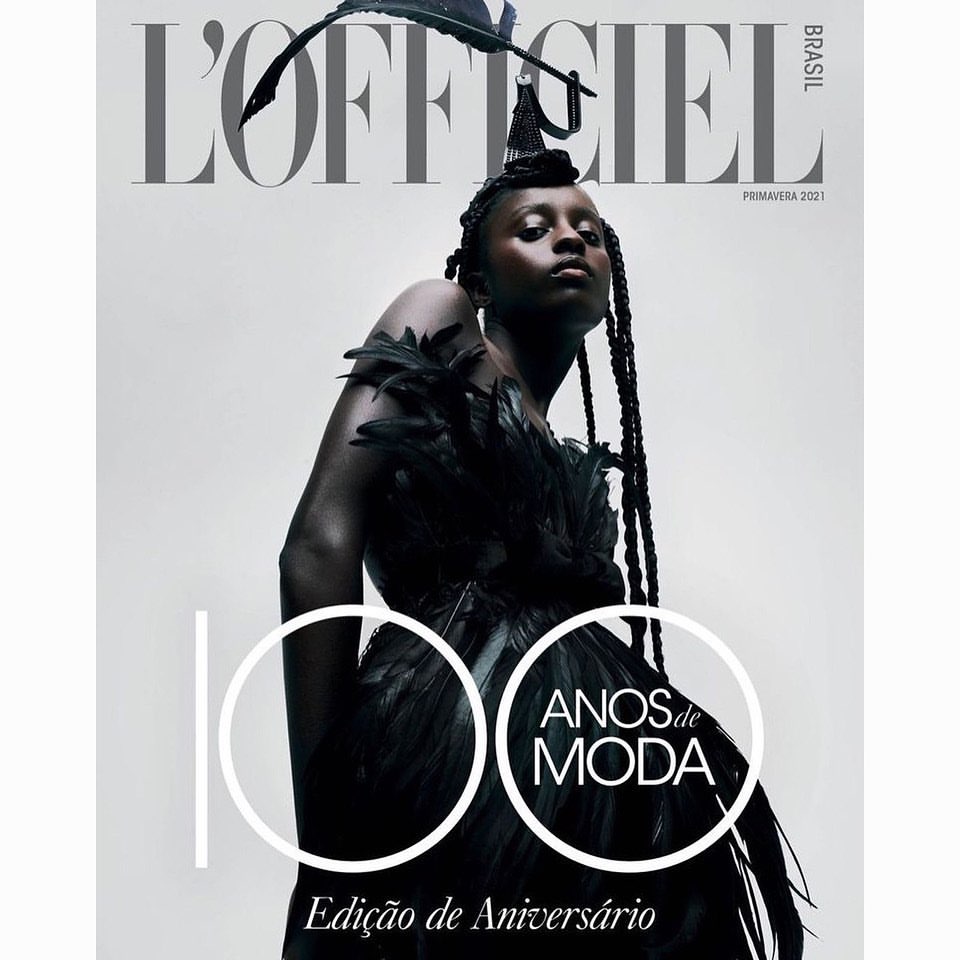 L'Officiel Brasil magazine cover featuring a model in a black feathered dress and headpiece against a white background.