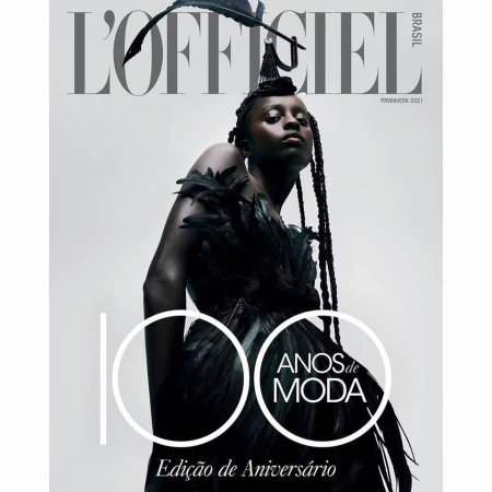 L'Officiel Brasil magazine cover featuring a model in a black feathered dress and headpiece against a white background.