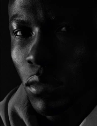 Close-up portrait of a Black man with dramatic low-key lighting highlighting facial features by photographer Gui Paganini.