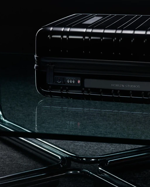 Black hard-shell luggage on a glass table against a dark background, highlighting travel gear and product photography.