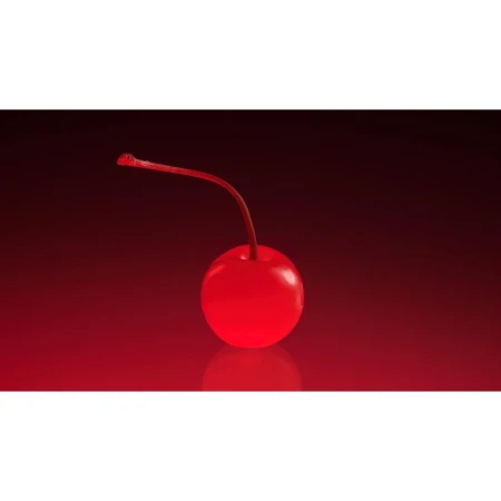Close-up studio shot of a shiny red maraschino cherry with its stem against a dark red gradient background with a reflective surface.