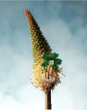 Floral-themed jewelry displayed on a flower stalk against a sky backdrop, showcasing fine craftsmanship and natural elegance.