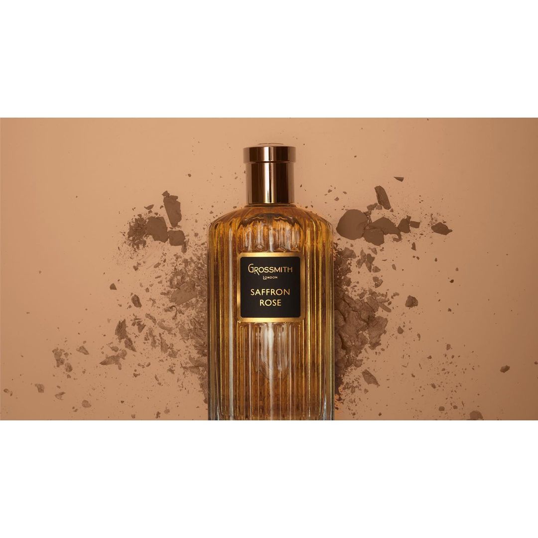 Grossmith Saffron Rose perfume bottle on a beige background with scattered powder for beauty and product marketing imagery.