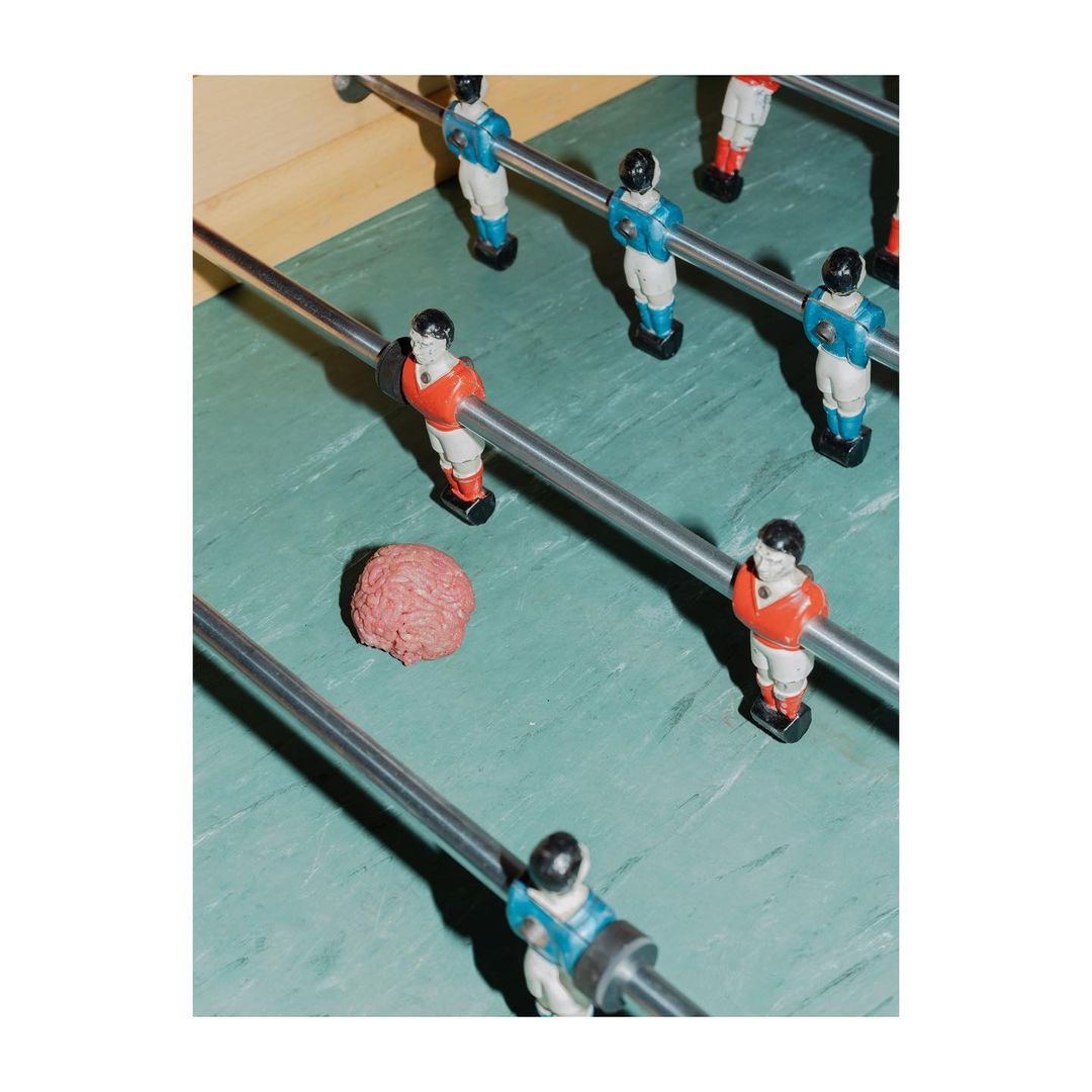 Overhead shot of foosball table with red and blue player figurines, silver rods, and a ball; sports and recreation equipment.