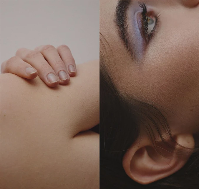 Closeup studio shot of a woman's face with blue eyeshadow, paired with a hand resting on skin, creating a minimalist beauty composition.