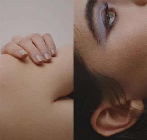 Closeup studio shot of a woman's face with blue eyeshadow, paired with a hand resting on skin, creating a minimalist beauty composition.