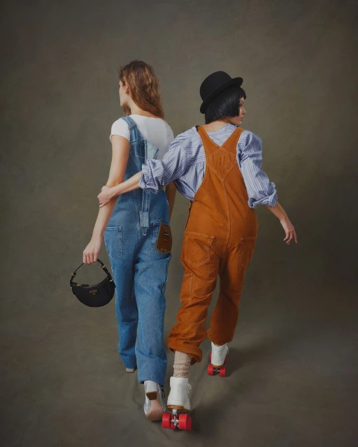 Two people on roller skates, one in blue overalls carrying a purse, the other in brown overalls and a bowler hat, walking away.