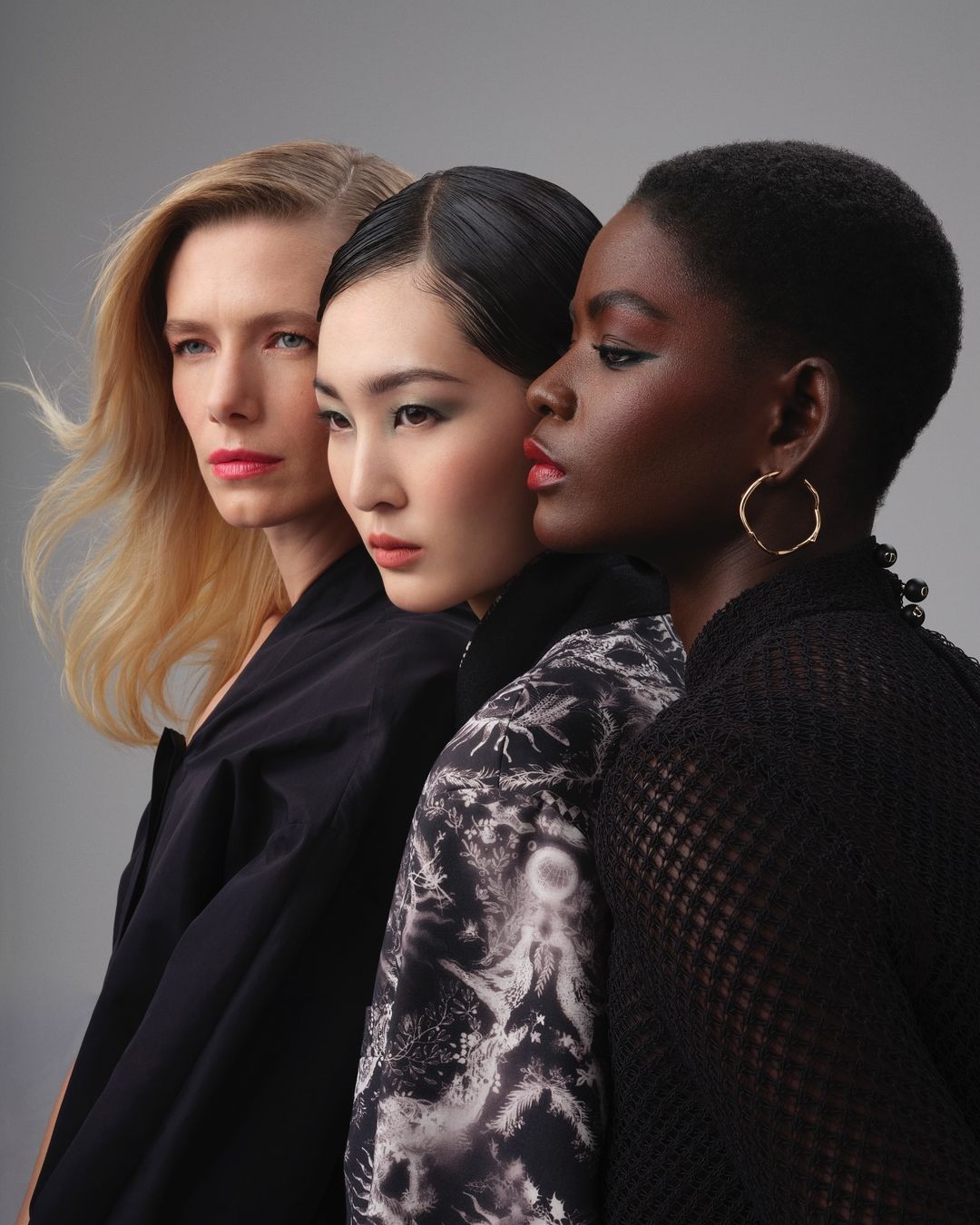 Three female models posing closely together in profile against a neutral grey background by photographer Guillaume Millet.