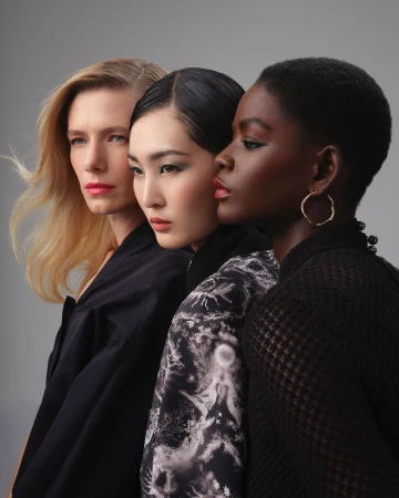 Three female models posing closely together in profile against a neutral grey background by photographer Guillaume Millet.
