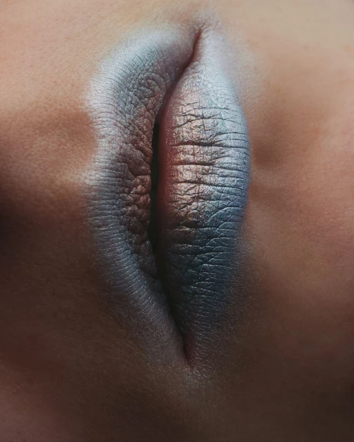 Extreme close-up of an eye with a silver and blue smokey eye makeup look, showcasing beauty and makeup artistry.