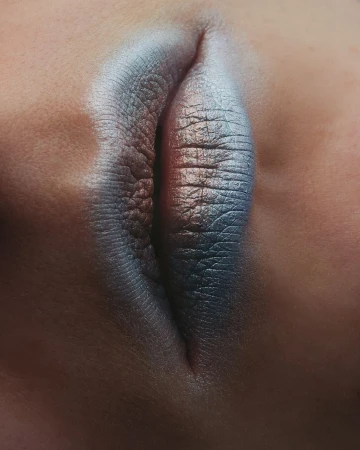 Extreme close-up of an eye with a silver and blue smokey eye makeup look, showcasing beauty and makeup artistry.
