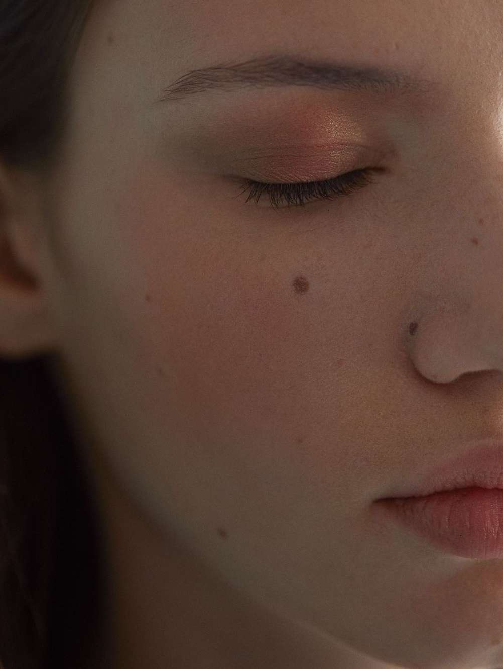 Close-up portrait of a woman with closed eyes, natural skin texture, and soft warm lighting by Guillaume Millet.
