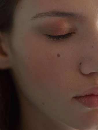 Close-up portrait of a woman with closed eyes, natural skin texture, and soft warm lighting by Guillaume Millet.