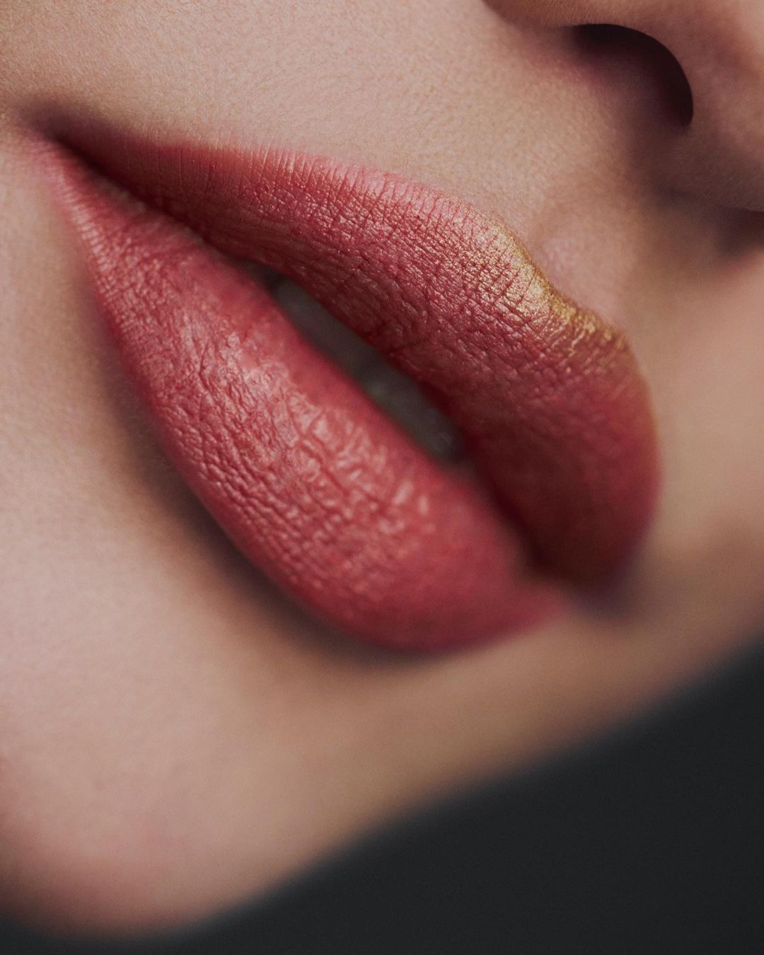 Close-up of a woman's face showcasing red lipstick on full lips, emphasizing beauty and makeup details against a blurred background.