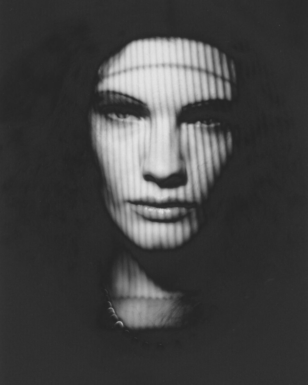 Black and white studio portrait of a mannequin head with light and shadow creating a striped pattern across the face and head.