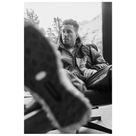 Monochrome portrait of a man seated in an office chair with a sneaker sole heavily blurred in the extreme foreground, photographed by Gus and Lo.