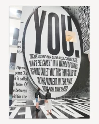 Two people standing in front of a giant wall installation featuring bold typography and text by Gus Powell.