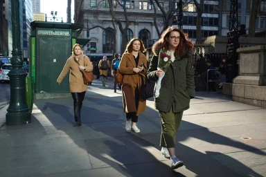 Three women walking along a sunny New York City sidewalk near Bryant Park News kiosk