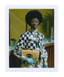 Polaroid photograph by Gus Van Sant in Paris featuring a woman wearing a checked jacket, large glasses, and holding a yellow handbag.
