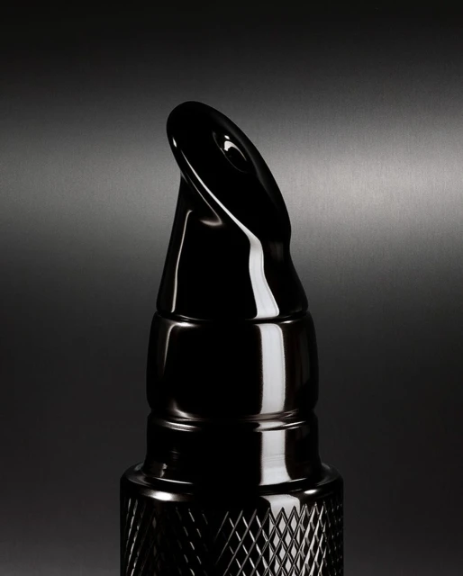 Close-up of a sleek black bottle with a unique applicator, set against a dark gray background, highlighting its glossy texture.