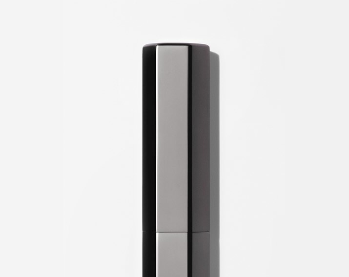 Close-up studio shot of sleek, modern silver and black cosmetic container against a bright white background, emphasizing minimalist design.