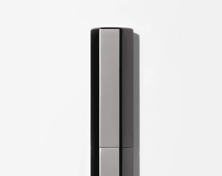 Close-up studio shot of sleek, modern silver and black cosmetic container against a bright white background, emphasizing minimalist design.