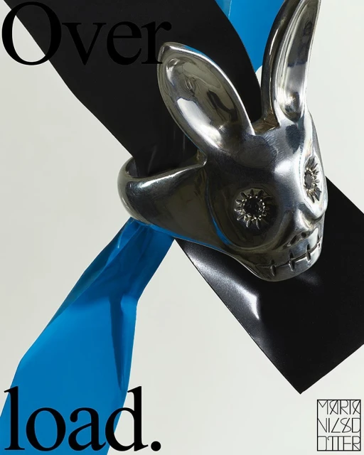 Silver rabbit ring showcased on a white backdrop with a black square and a blue ribbon; contemporary jewelry advertisement.