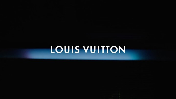 Louis Vuitton brand name in white against a dark background with a blue and purple horizontal gradient light.